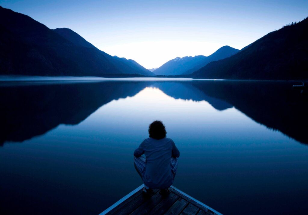 Man with awakened kundalini meditate in front of a lake