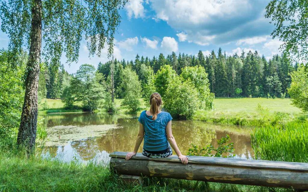 Woman meditating looking at a lake for spiritual journey